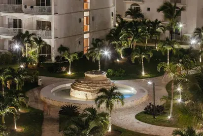 a courtyard with a fountain in front of a building with palm trees at 1 Sol Dominicus Solo Adultos Habitación con Entrada Independiente y Baño Privado in Bayahibe