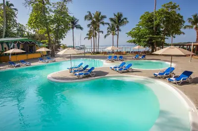 a pool with chairs and umbrellas in a resort at Hotel whala!boca chica - All Inclusive in Boca Chica