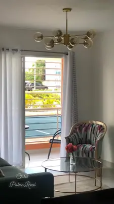 a living room with a chair and a table and a window at Oasis Palma Real santiago, Republica Dominicana in Santiago de los Caballeros