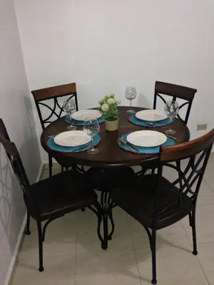 a wooden table with chairs and plates and wine glasses at Caribbean Seaview apart Malecon Santo Domingo in Santo Domingo