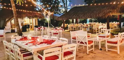 a restaurant with white tables and chairs and lights at Hotel Atlantis in Las Terrenas