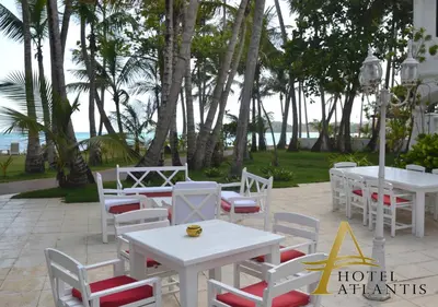 a group of tables and chairs with the ocean in the background at Hotel Atlantis in Las Terrenas