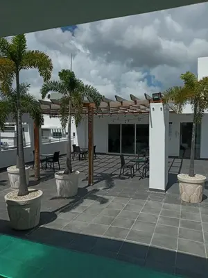a patio with palm trees and tables and a building at Cozy apartment in exclusive area Bella Vista in Santo Domingo