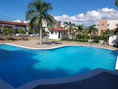 a large blue swimming pool with a palm tree at Paradise 3 cerro Altos in Santiago de los Caballeros