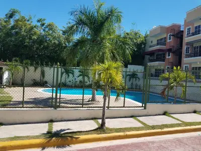 a fence with palm trees in front of a swimming pool at Paradise 3 cerro Altos in Santiago de los Caballeros