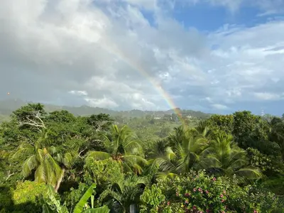 a rainbow in the sky over a forest of trees at Villa Coconut in La Verita