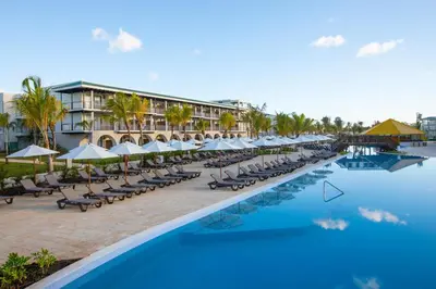 a resort with a pool with chairs and umbrellas at Ocean el Faro Resort - All Inclusive in Punta Cana