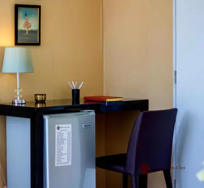 a desk with a chair and a refrigerator in a room at Hotel Santa Clara in San Fernando de Monte Cristi