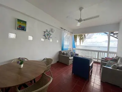 a living room with a table and chairs and the ocean at Apartamentos Magallanes Bayahibe in Bayahibe