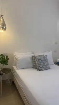 a bed with white sheets and pillows in a room at Apartamentos Magallanes Bayahibe in Bayahibe