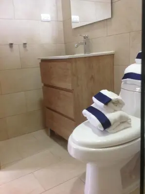 a bathroom with a toilet and a sink and towels at Mi Hogar Jarabacoa in Jarabacoa