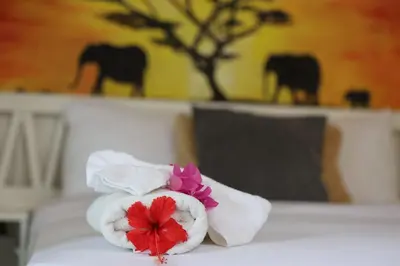 a pile of towels with flowers on a bed at Afreeka Beach Hotel in Las Terrenas