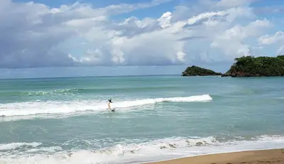 a person riding a wave on a surfboard in the ocean at Las Terrenas, La Fenice, Playa Popy in Las Terrenas