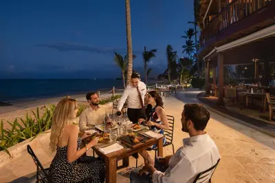 a group of people sitting at a table on the beach at Impressive Premium Punta Cana - All Inclusive in Punta Cana