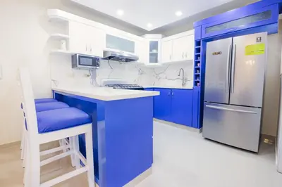 a blue and white kitchen with a refrigerator and a stool at Dolce Villas at Harmony 2 in Santiago de los Caballeros