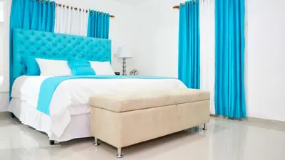 a bedroom with a large bed with blue curtains and a chair at Dolce Villas at Harmony 2 in Santiago de los Caballeros