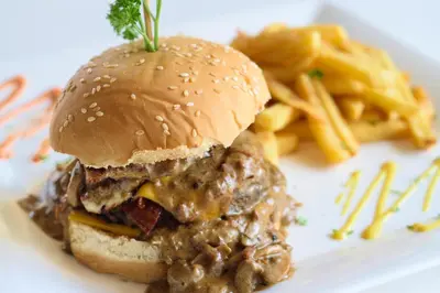 a sandwich on a white plate with french fries at Puerto Blanco Marina & Hotel in Puerto de Luperon