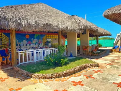 a resort on the beach with a grass roof at Puerto Blanco Marina & Hotel in Puerto de Luperon
