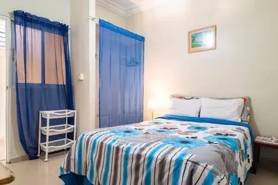 a bedroom with a bed and a window with blue curtains at Cerca del Mar, Obelisco Hembra y Zona Colonial in Santo Domingo