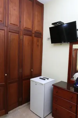 a small kitchen with a white refrigerator and a dresser at Hotel Aluge in Santo Domingo