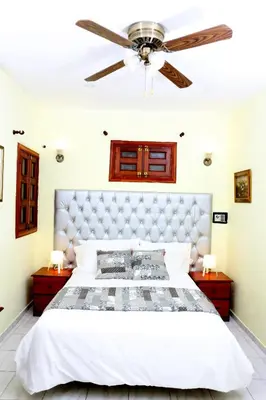 a bedroom with a large white bed with a ceiling fan at Hotel Aluge in Santo Domingo