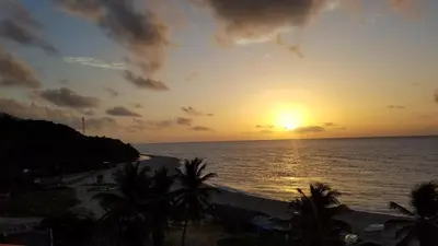 a sunset over the ocean with palm trees at Hotel Vista Sur in Los Patos