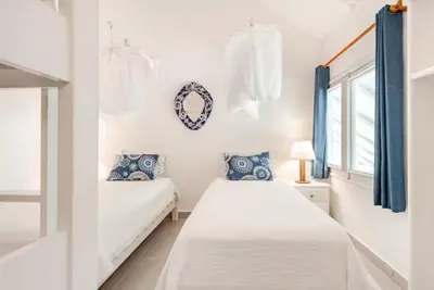 two beds in a white room with blue curtains at Caribbean Beach Villa Playa Bonita Las Terrenas in Las Terrenas