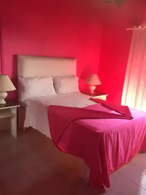 a red bedroom with a bed and two lamps at Hotel Maracas Punta Cana in Punta Cana