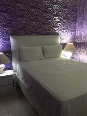 a bedroom with a bed with a purple wall at Hotel Maracas Punta Cana in Punta Cana