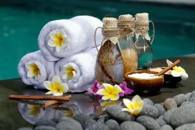 a pile of towels and a bottle of soap and flowers at Hotel Maracas Punta Cana in Punta Cana