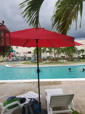 a red umbrella next to chairs and a pool at PARADISE 3 Cerro Altos in Santiago de los Caballeros
