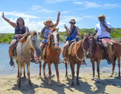 a group of people riding horses on the beach at HappiCasaRD & Holistic House in Sosúa