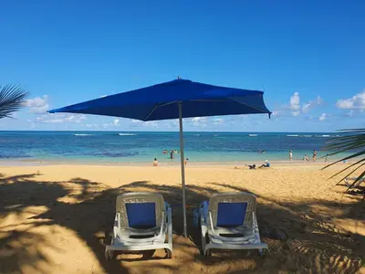 two chairs under an umbrella on a beach at Palmeraie Terrenas Beach Apartment in Las Terrenas