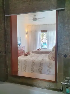 a mirror reflecting a bedroom with a bed and a window at Palmeraie Terrenas Beach Apartment in Las Terrenas