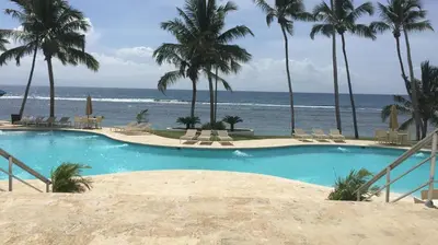 a swimming pool with the ocean in the background at Beachfront, Juandolio in Juan Dolio