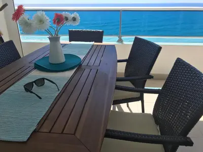 a dining room table with chairs and a vase with flowers at Beachfront, Juandolio in Juan Dolio