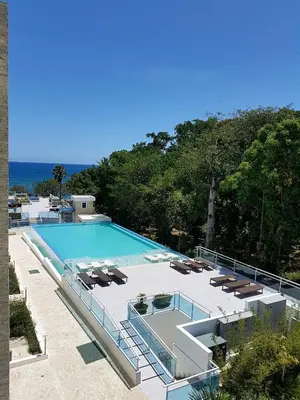 a large swimming pool with lounge chairs and the ocean at Koko and Suzy's ocean dream in Laguna del Higüero