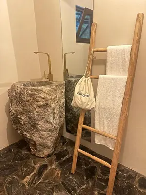 a bathroom with a rock sink and a wooden chair at El Rincon de Abi in Las Terrenas
