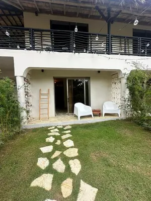 a patio with two white chairs and a ladder on the grass at El Rincon de Abi in Las Terrenas