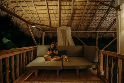 a woman sitting on a couch with a dog on a porch at El Valle Lodge in El Valle