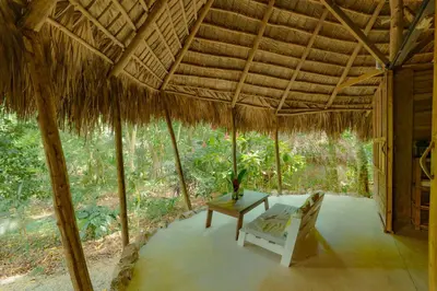 a room with a table and a chair in a straw roof at El Valle Lodge in El Valle