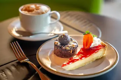 two desserts on a plate with a cup of coffee at Dreams La Romana All-Inclusive Resort & Spa in Bayahibe