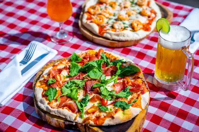two pizzas on a table with two glasses of beer at Dreams La Romana All-Inclusive Resort & Spa in Bayahibe