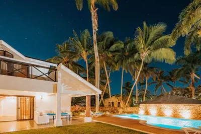 a villa with a swimming pool and palm trees at Condo Hotel Playa Las Ballenas in Las Terrenas