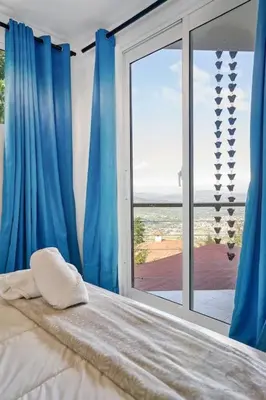 a bedroom with a bed and a large window at Mansion Dubai-Mountain-Jacuzzi-4BR-Jamaca De Dios in Jarabacoa