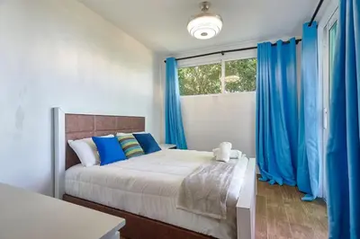 a bedroom with a large bed with blue curtains at Mansion Dubai-Mountain-Jacuzzi-4BR-Jamaca De Dios in Jarabacoa