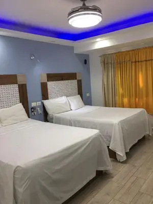 two beds in a hotel room with blue lighting at Hotel Restaurant Hamilton in Boca Chica