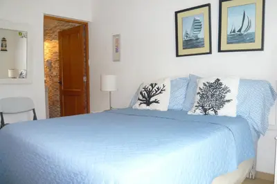 a white bedroom with a blue bed with two pillows at Cadaques Caribe Boulevard Dominicus Americanus Carretera a Bayahibe Vel 206 in Bayahibe