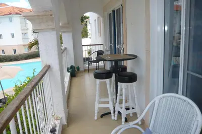 a balcony with a table and stools next to a pool at Cadaques Caribe Boulevard Dominicus Americanus Carretera a Bayahibe Vel 206 in Bayahibe