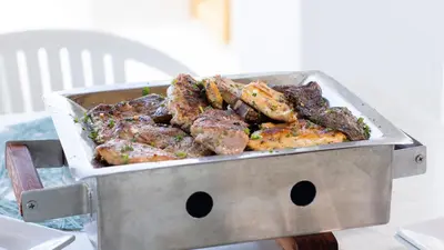 a grill with meat and potatoes on a table at Hotel Capriccio Mare y Restaurante in Punta Cana